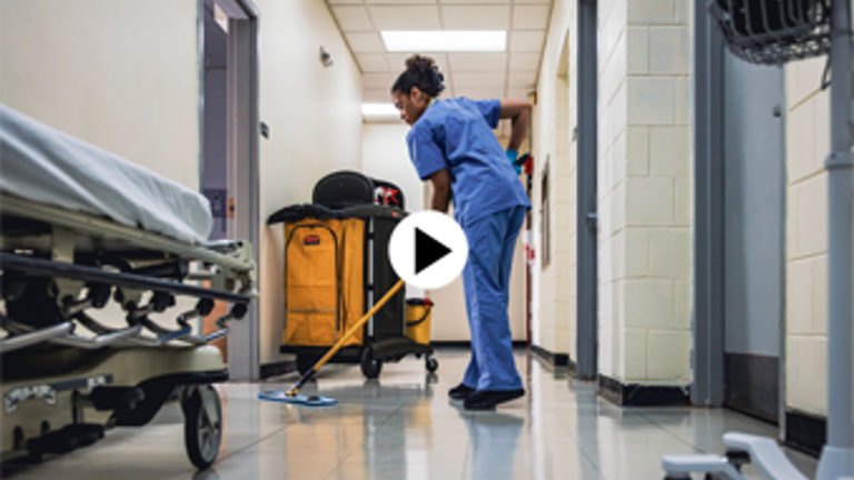 Healthcare worker cleaning hospital corridor with a mop