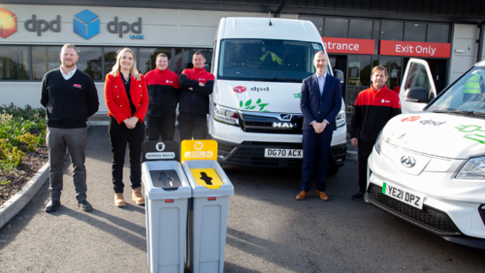 Three dpd employees in front of Rubbermaid recycling cans.