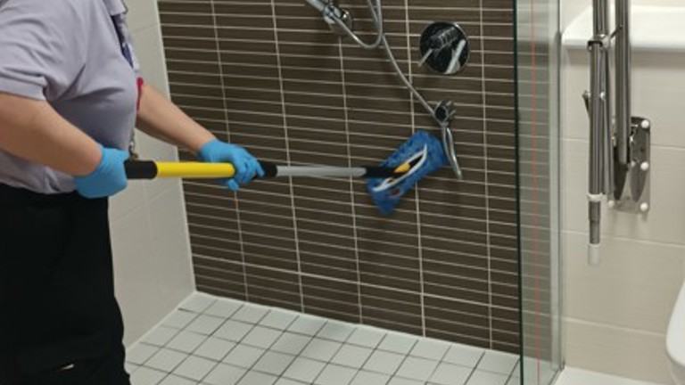 Person cleaning a shower with a brush