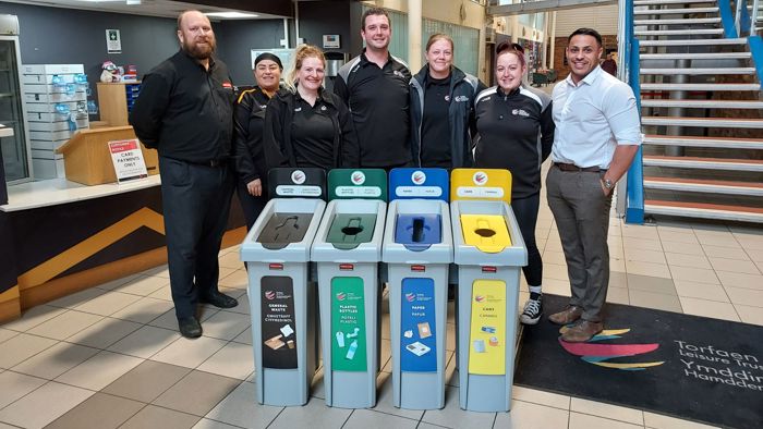Torfaen employees in front of Rubbermaid recycling cans.