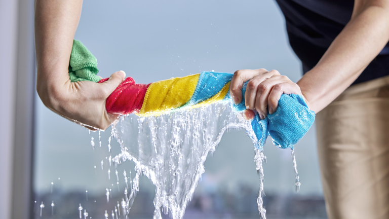 Hands wringing colorful cloth releasing water
